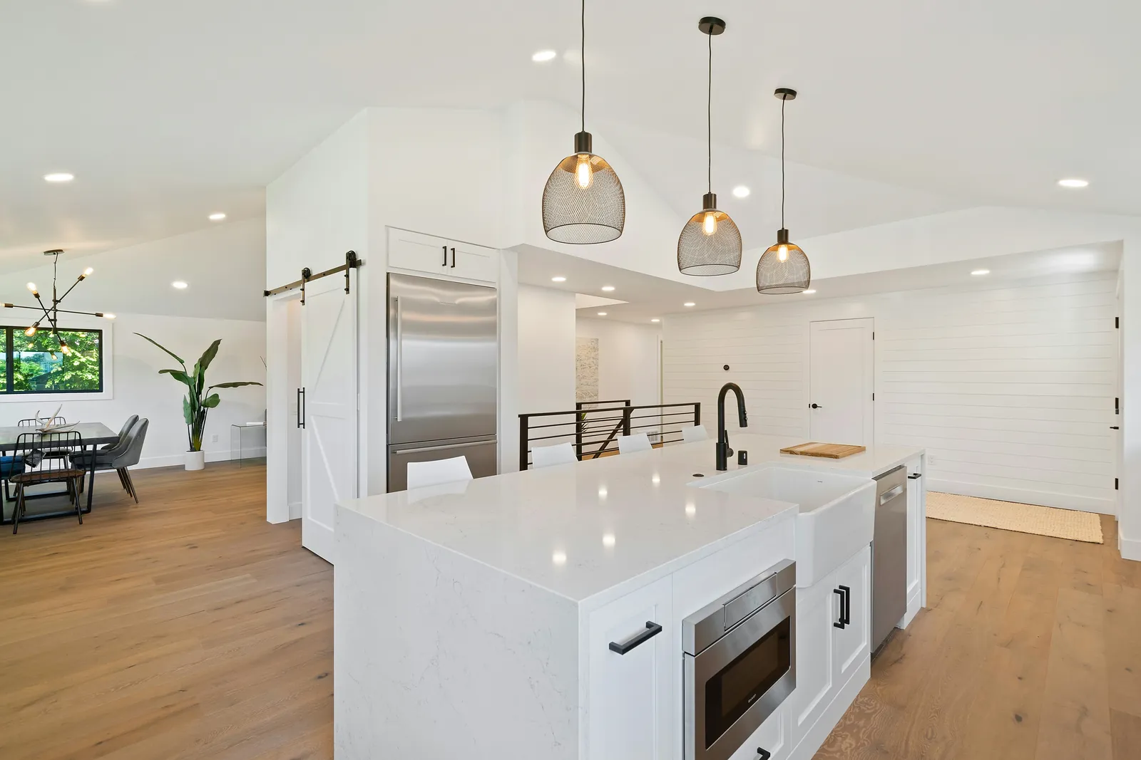 Remodeled white kitchen with quartz island and pendant lighting